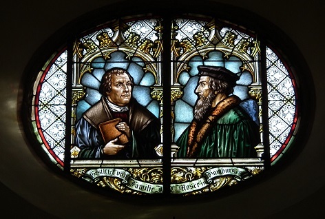 カルヴァン（右）が描かれたステンドグラス。左側はマルティン・ルター